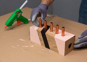 Após secagem da tinta, coloque os tubos de cobre em cada furo realizado.