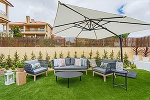 jardim com relva artificial, conjunto de sofás de jardim, almofadas, chapéu de sol e decoração