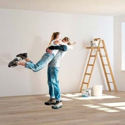 casal abraçado enquanto pinta paredes de casa