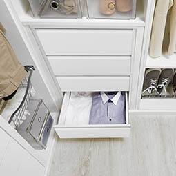 móvel branco, com uma gaveta aberta e roupa no seu interior