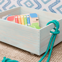 Caixa carrinho azul com uma pega de corda azul e com vários brinquedos lá dentro