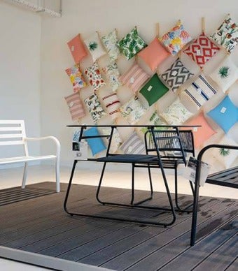 Conjunto de banco de ferro com mesa e cadeira, parede decorada com almofadas de exterior